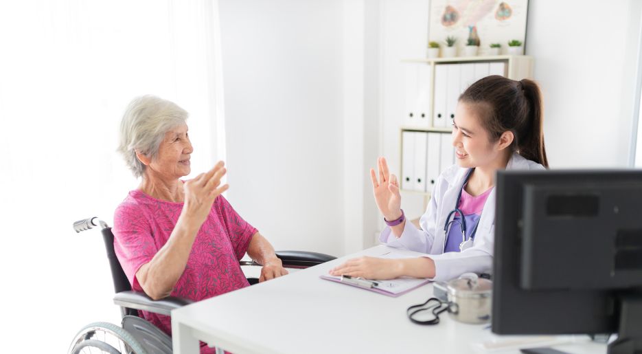 Ärztin in Gespräch mit Patientin im Rollstuhl